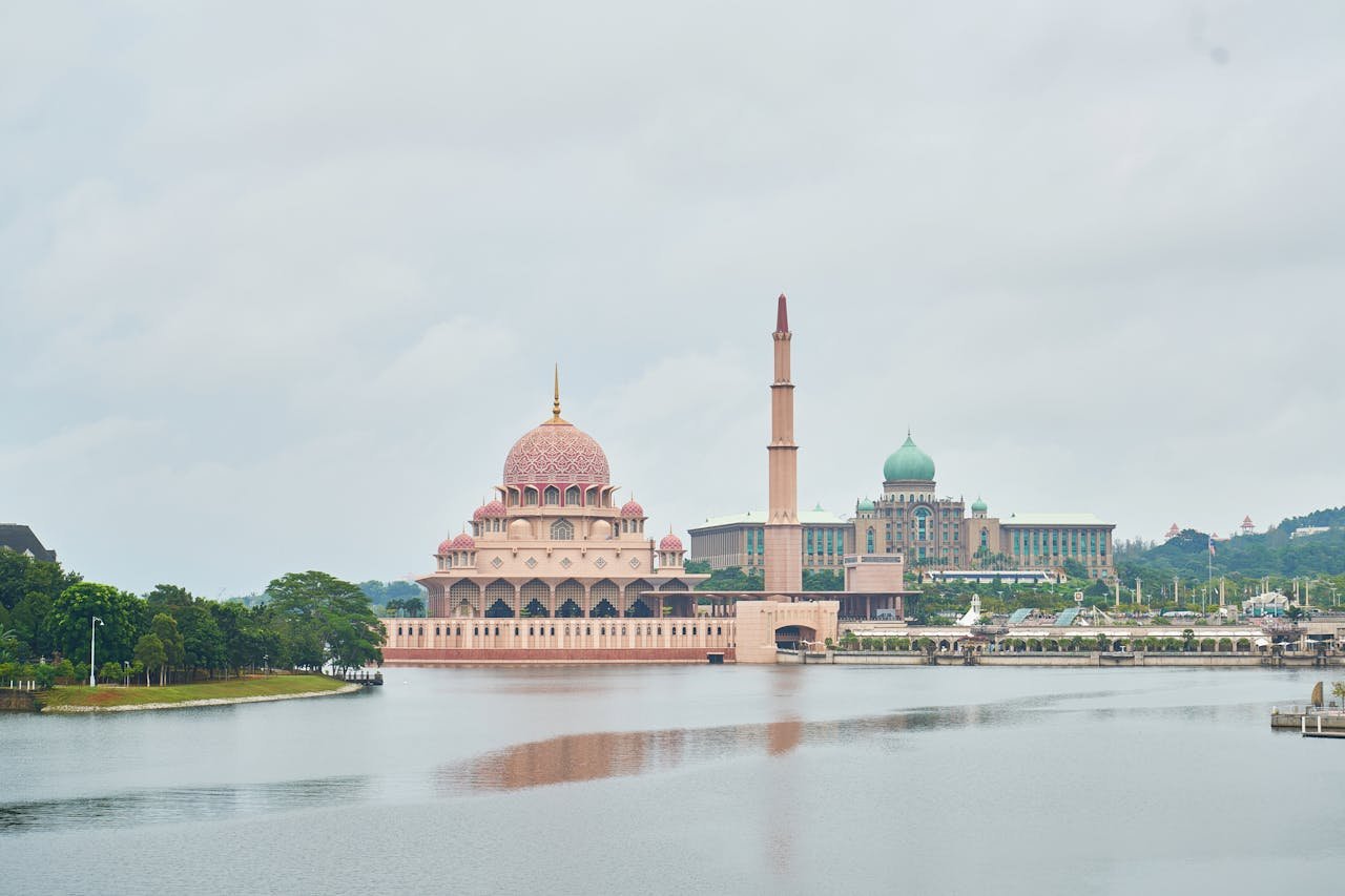 Captivating view of the Putra Mosque by the lake in Putrajaya, Malaysia, surrounded by lush greenery.